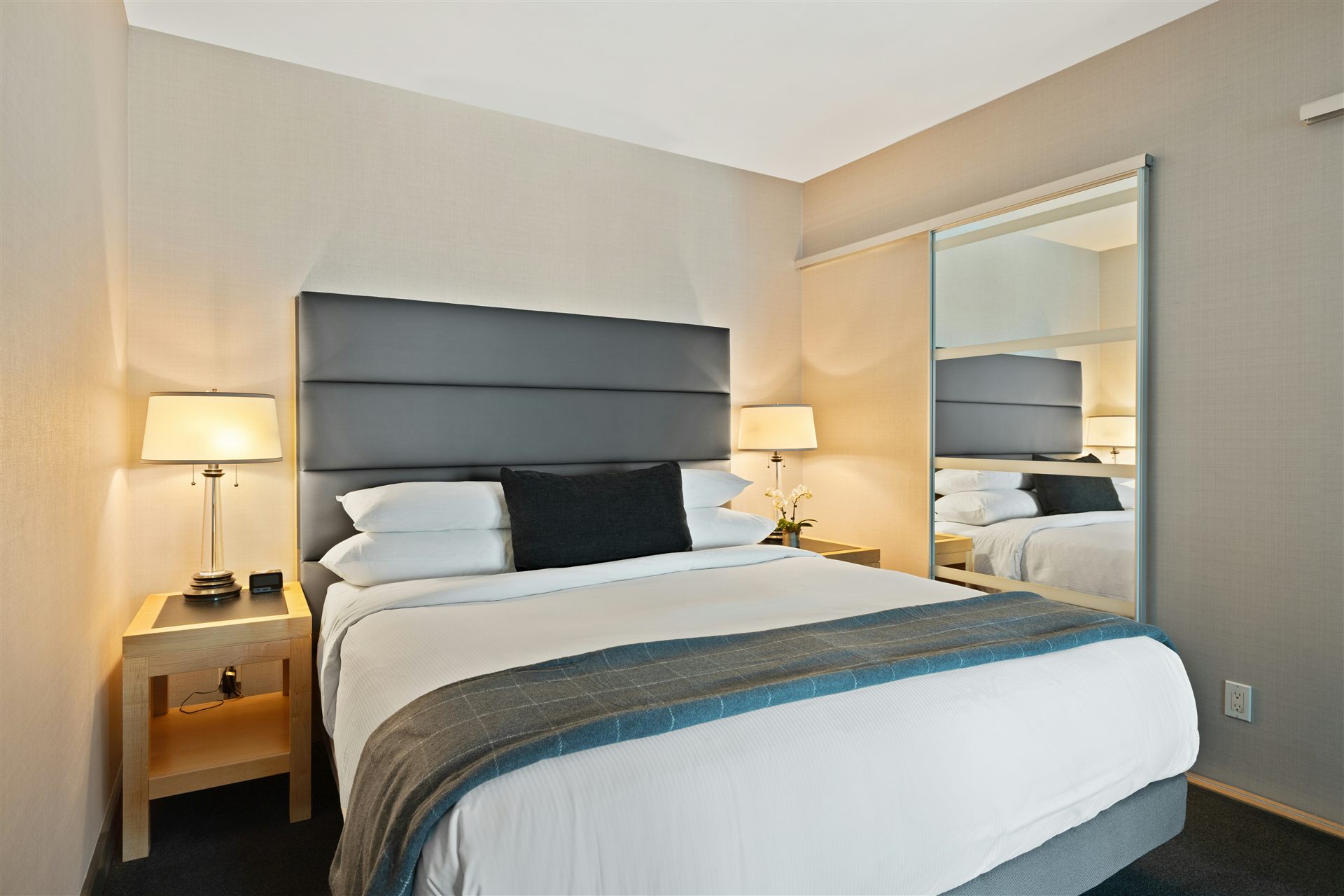 Compact hotel room with bed and mirror